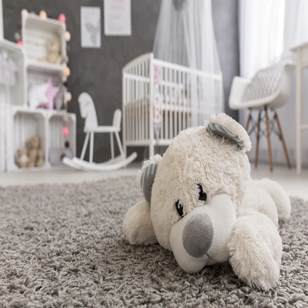 Plush grey nursery room carpet with a teddy bear