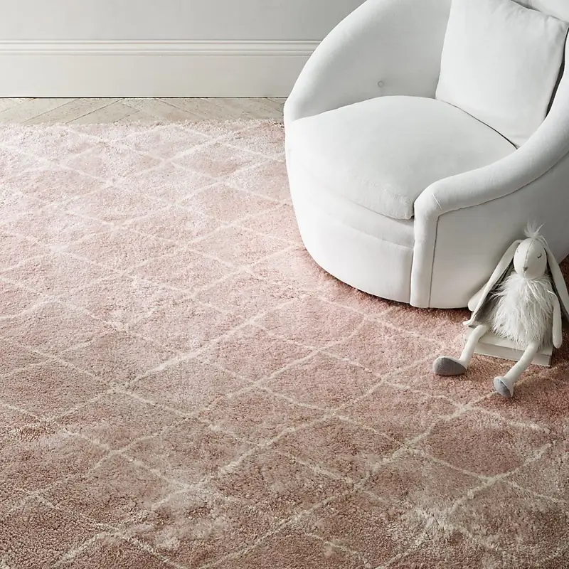 Soft pink shaggy nursery rug with white diamond trellis design.