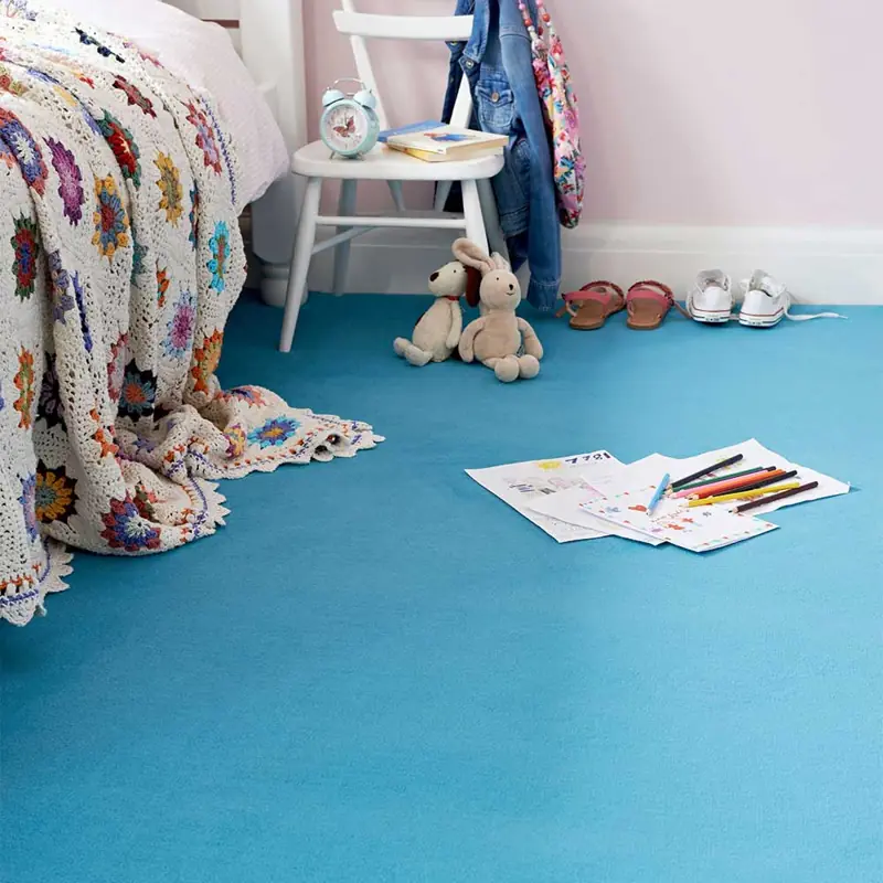 Vibrant blue wall-to-wall carpet in a child's bedroom with toys and drawings.