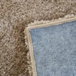 Corner of plush brown carpet showing anti-slip backing