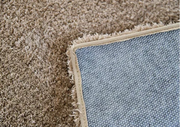 Corner of plush brown carpet showing anti-slip backing