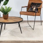 Cream area rug under a round wood table and leather chair