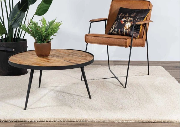 Cream area rug under a round wood table and leather chair
