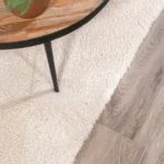 Cream rug under wooden coffee table on light wood floor