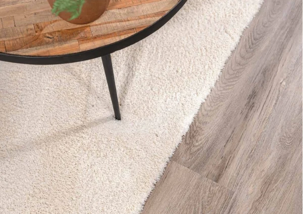 Cream rug under wooden coffee table on light wood floor