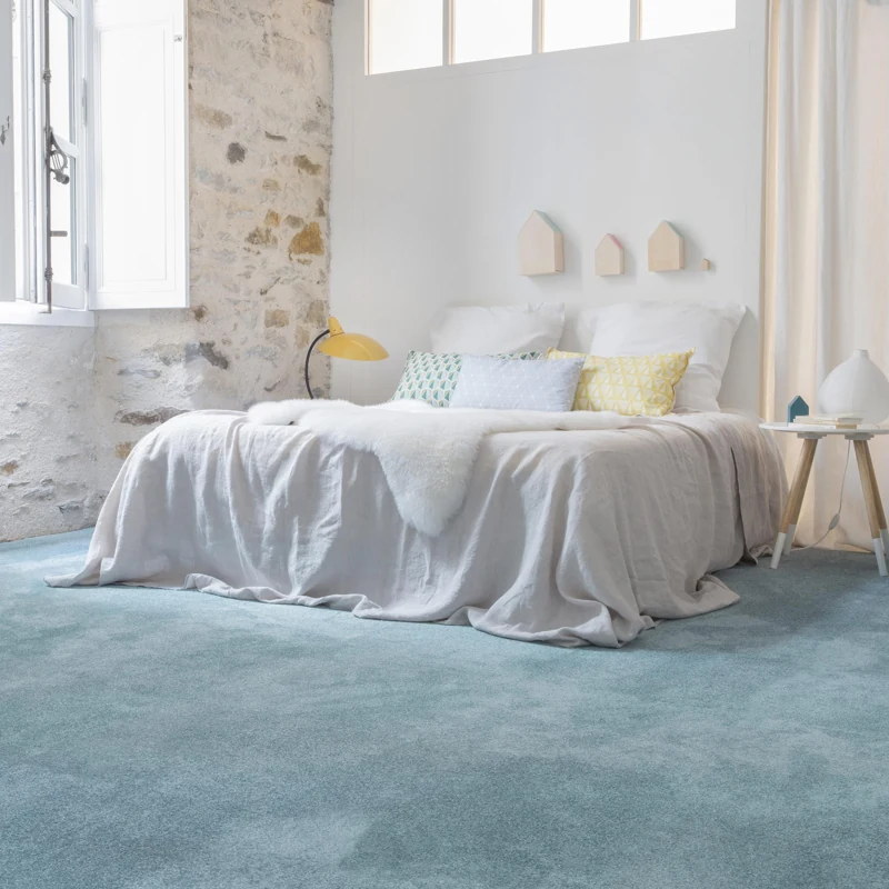 Plush light blue wall-to-wall carpet in bright bedroom