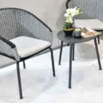 Two grey woven chairs and small table set on a white rug