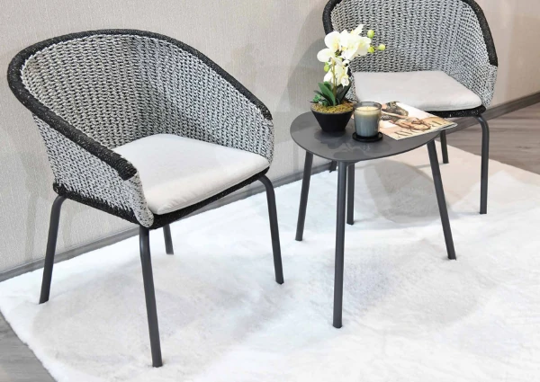 Two grey woven chairs and small table set on a white rug